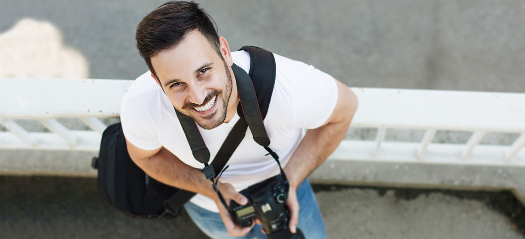Hombre sonriendo con una cámara entre sus manos 